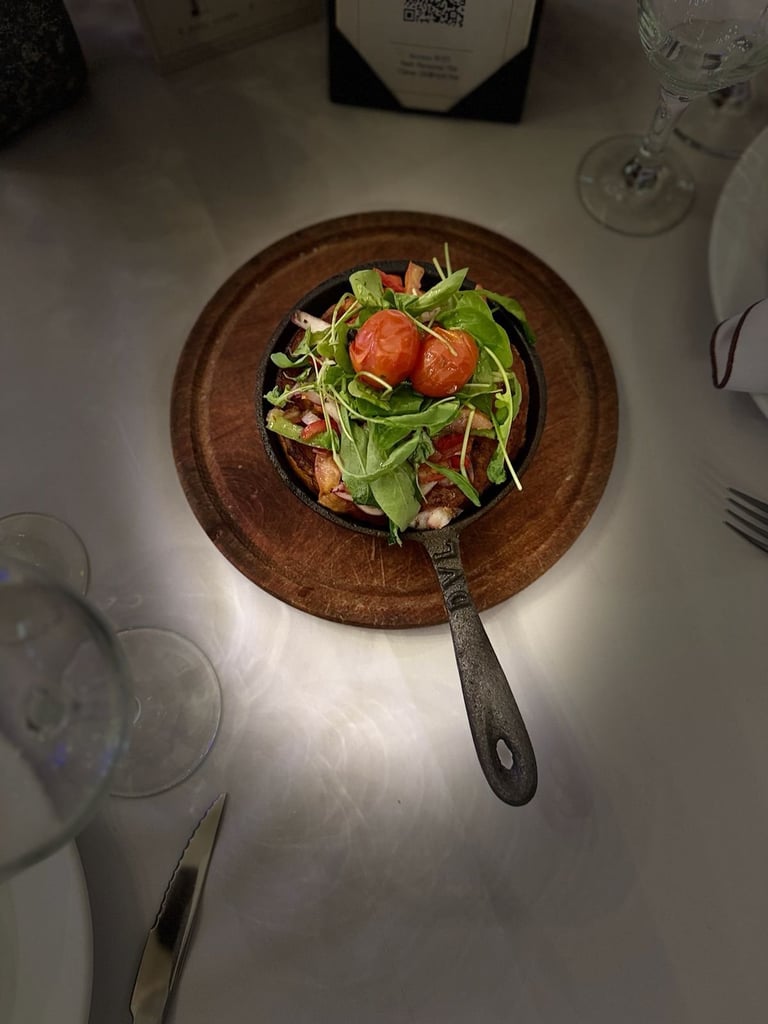 Plated arugula salad with tomatoes and croutons on a wooden board at fine dining table