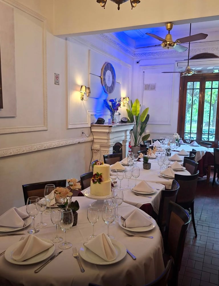 Elegant dining room with round tables set for formal dinner, white linens, blue accent lighting, and decorative floral centerpieces